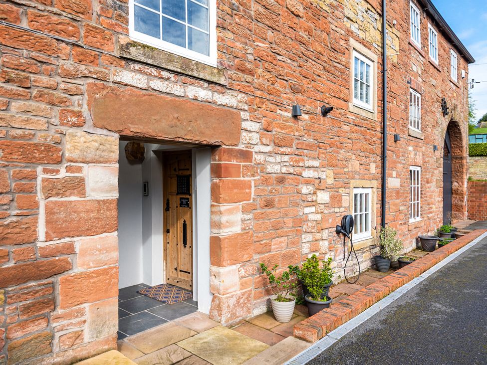 An entrance with a wooden door and stone wall at Carleton Mill Cottage in Carlisle