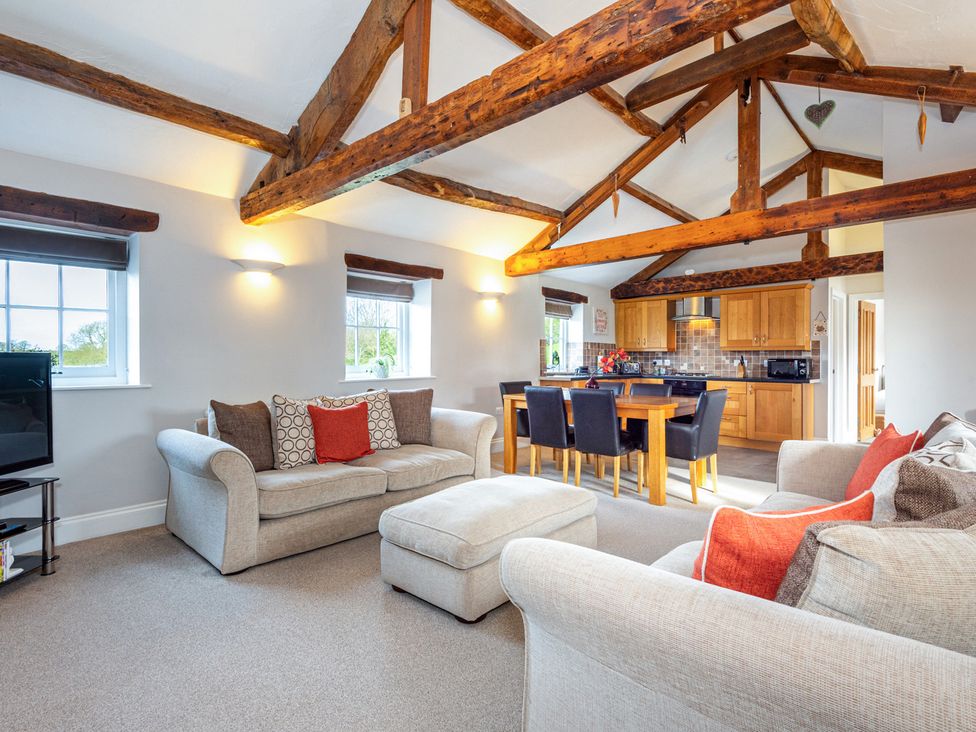 A living room with a sofa, television, and dining area at Carleton Mill Cottage in Carlisle