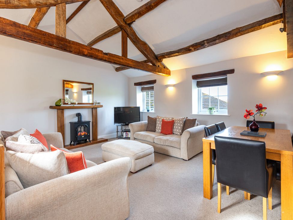 A living room with a sofa, fireplace and dining area at Carleton Mill Cottage in Carlisle