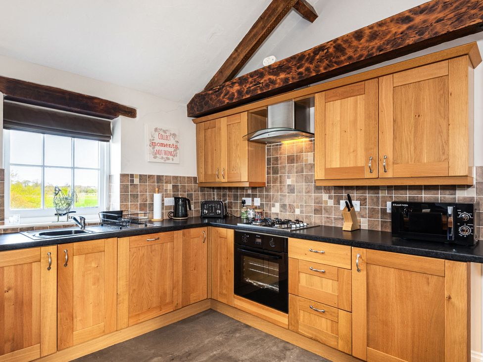 A kitchen with wooden cabinets and appliances at Carleton Mill Cottage in Carlisle