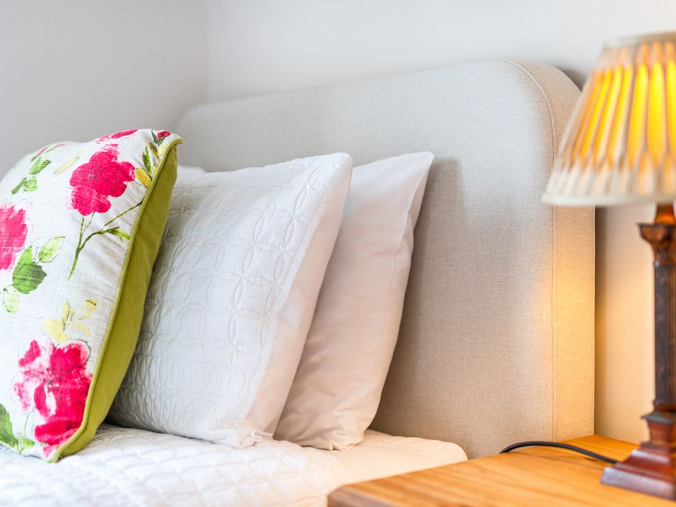 A bed with pillows and a lamp at Carleton Mill Cottage in Carlisle