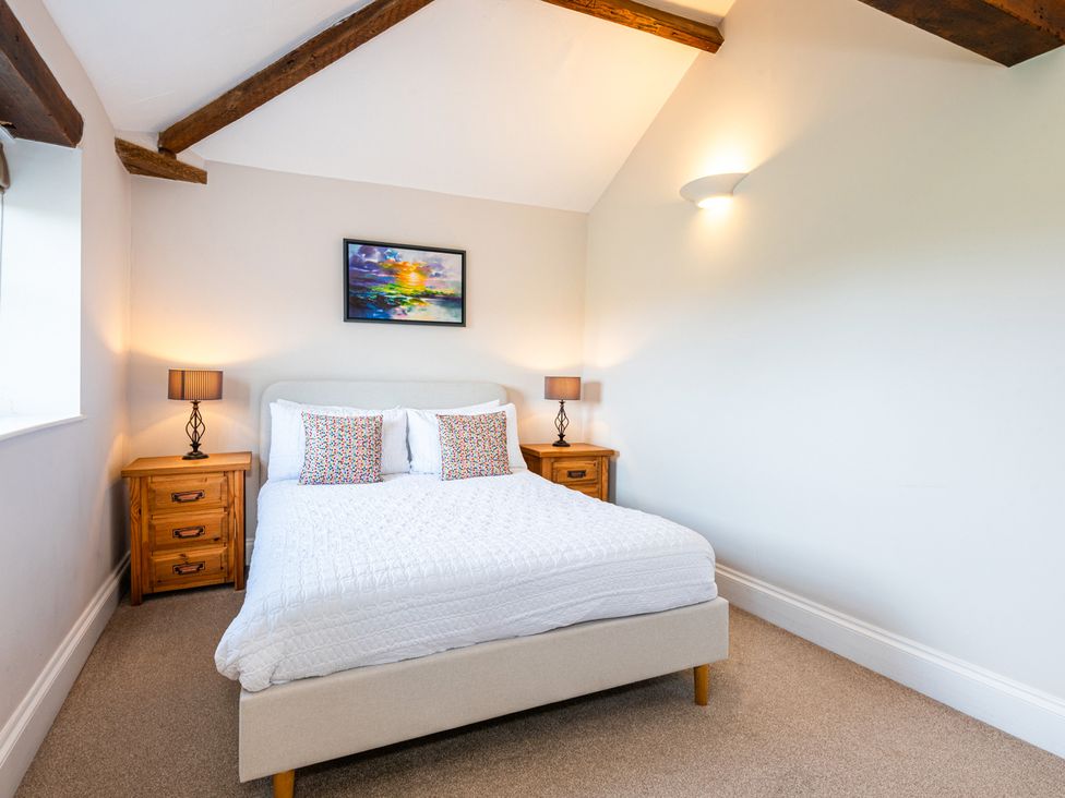 A bedroom with a bed and nightstands at Carleton Mill Cottage in Carlisle