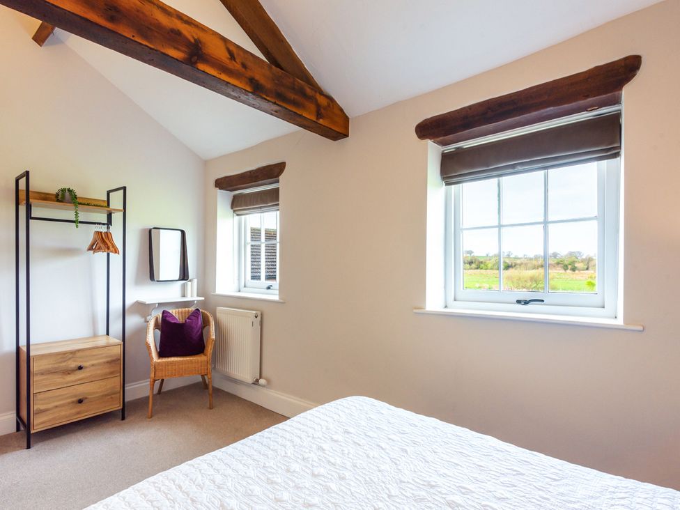 A bedroom with a window, chair, and clothing rack at Carleton Mill Cottage in Carlisle