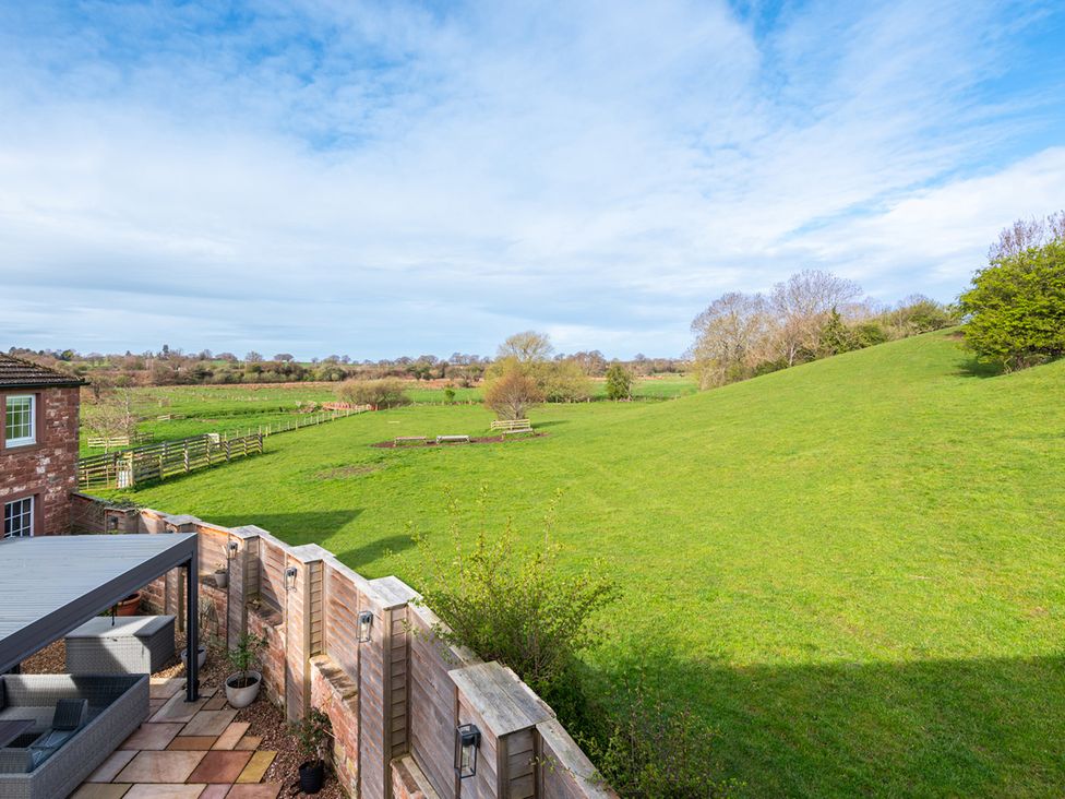 A view of a green field with trees and hills at Carleton Mill Cottage in Carlisle