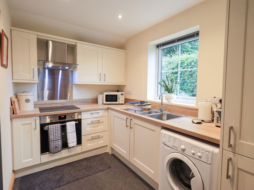 A kitchen with a stove, sink, and washing machine at Rose Cottage, Crosby on Eden near Carlisle