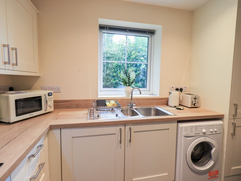 A kitchen with a sink and washing machine at Rose Cottage in Crosby on Eden near Carlisle