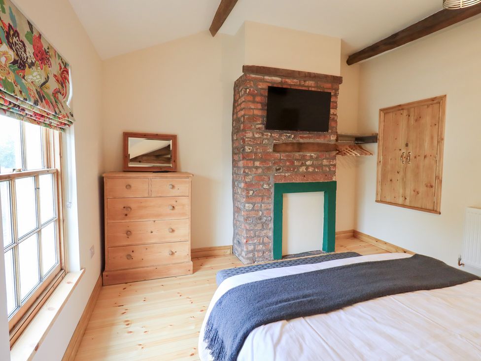 A bedroom with a fireplace and dresser at Rose Cottage Crosby on Eden near Carlisle