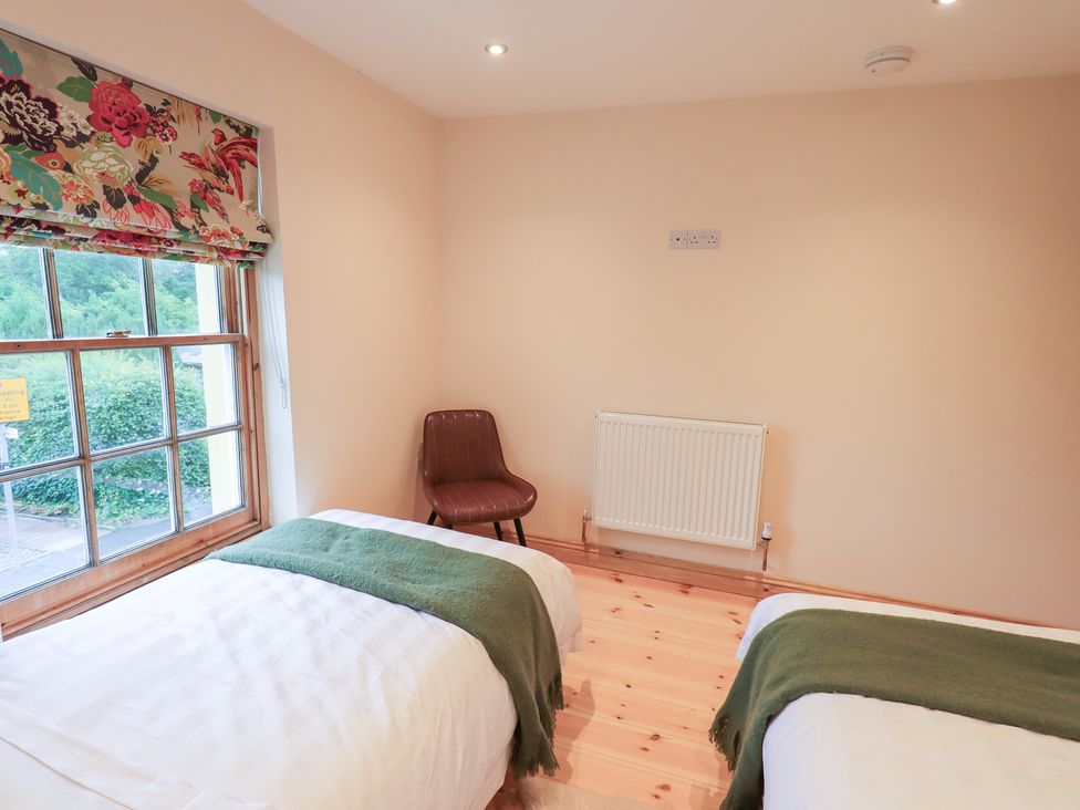 A bedroom with two beds and a chair at Rose Cottage in Crosby on Eden near Carlisle