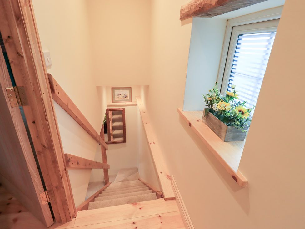 A staircase with a flower arrangement on a windowsill at Rose Cottage in Crosby on Eden near Carlisle