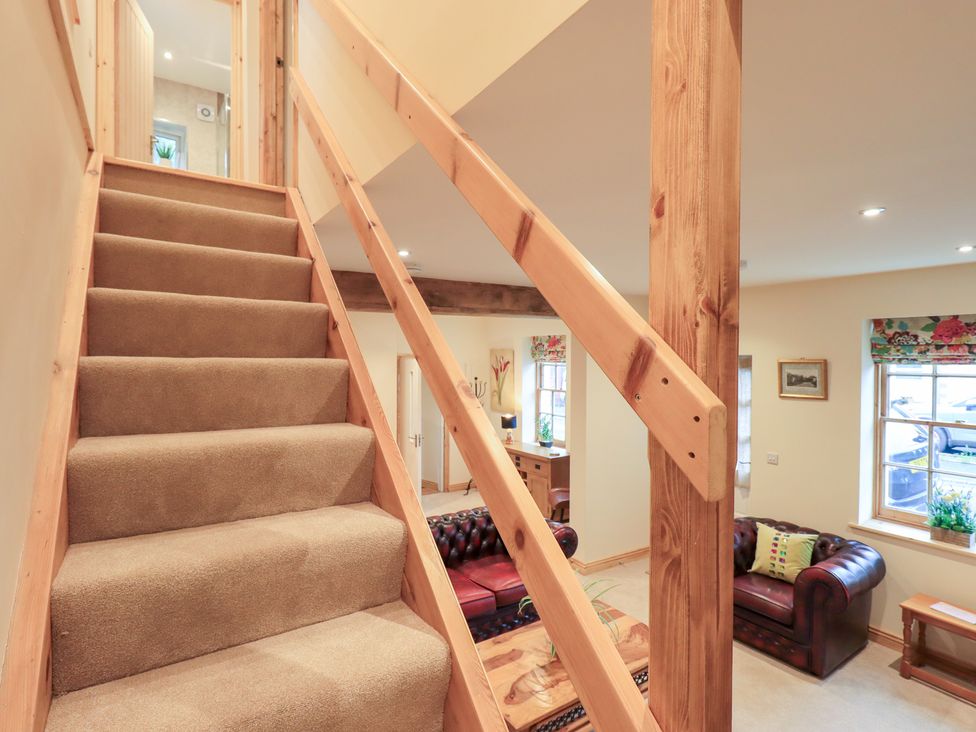 A staircase with wooden railing and sofa visible at Rose Cottage in Crosby on Eden near Carlisle
