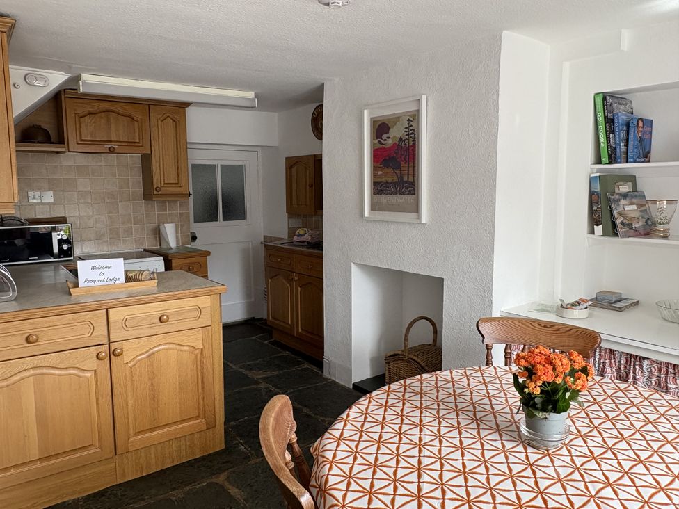 A kitchen with wooden cabinets and a table at Prospect Lodge in Portinscale