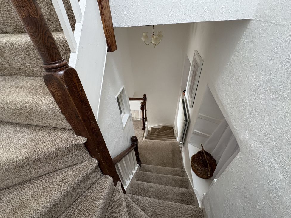 A staircase with a handrail and chandelier at Prospect Lodge in Portinscale