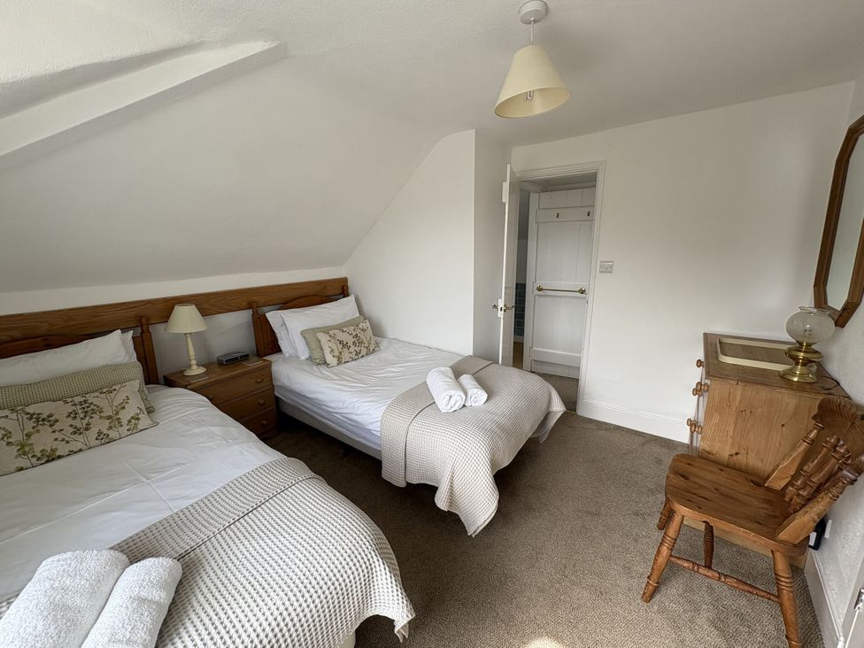 A bedroom with two beds and a wooden chair at Prospect Lodge in Portinscale