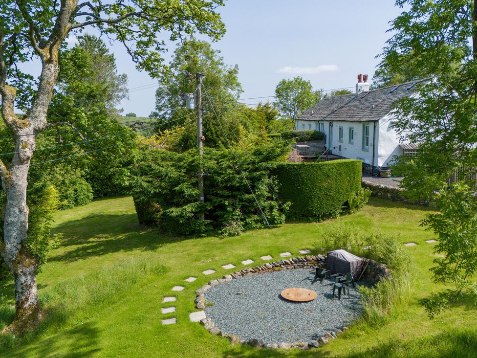 An outdoor area with a circular fire pit and chairs at Mell View Cottage Ullswater