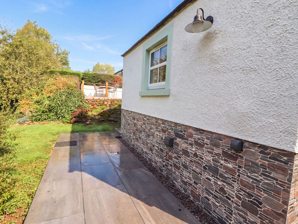 An outdoor area with a stone wall and paved path at Mell View Cottage in Ullswater