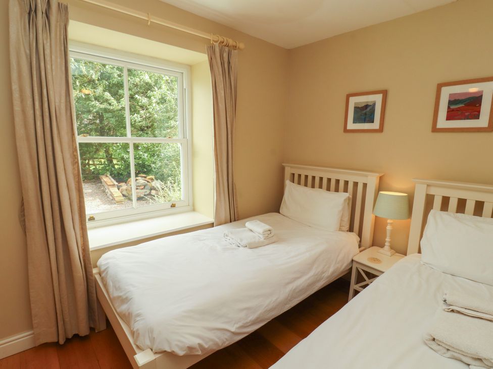 A bedroom with two beds and a window at Mell View Cottage, Ullswater