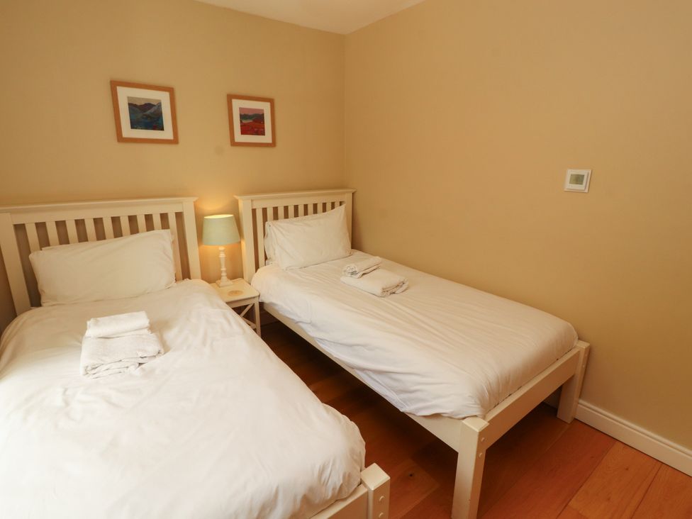 A bedroom with two beds and a bedside table at Mell View Cottage in Ullswater