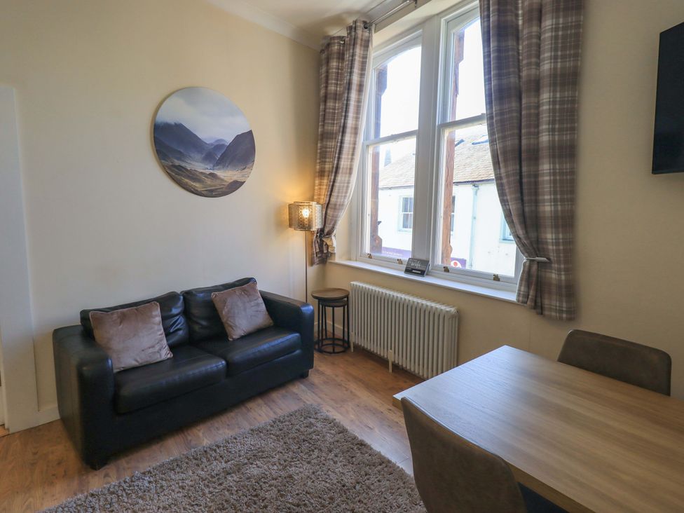 A living room with a sofa and dining table at St Johns View in Keswick