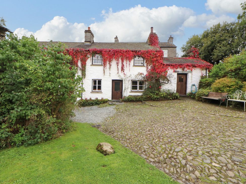 A house with ivy on the wall and a path in the garden at Mill Cottage in Garnett Bridge