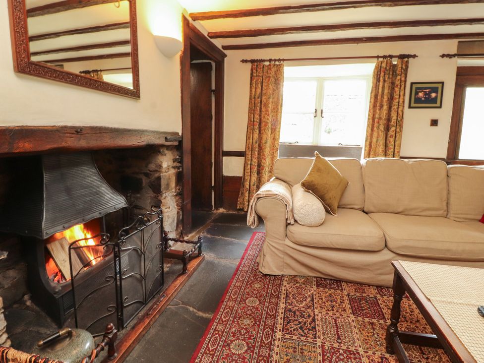 A living room with a fireplace and a sofa at Mill Cottage in Garnett Bridge