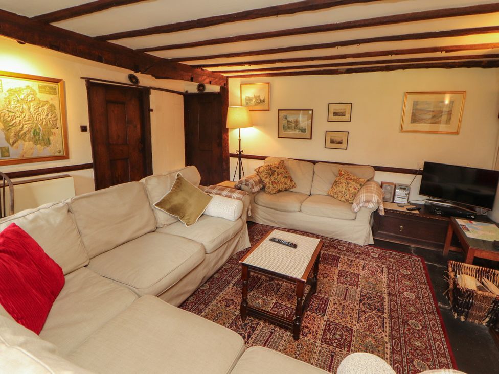 A living room with a sofa, coffee table, and television at Mill Cottage in Garnett Bridge
