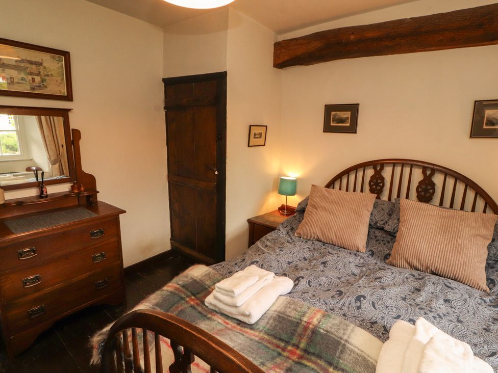 A bedroom with a bed and dresser at Mill Cottage in Garnett Bridge