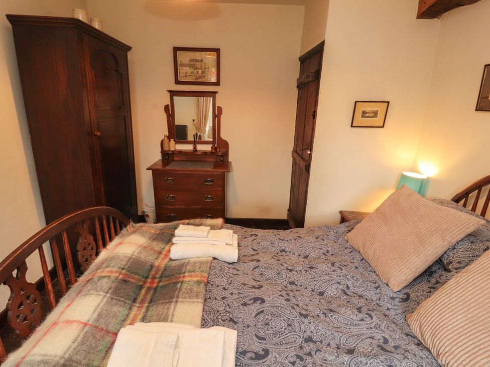 A bedroom with a bed and dresser at Mill Cottage in Garnett Bridge