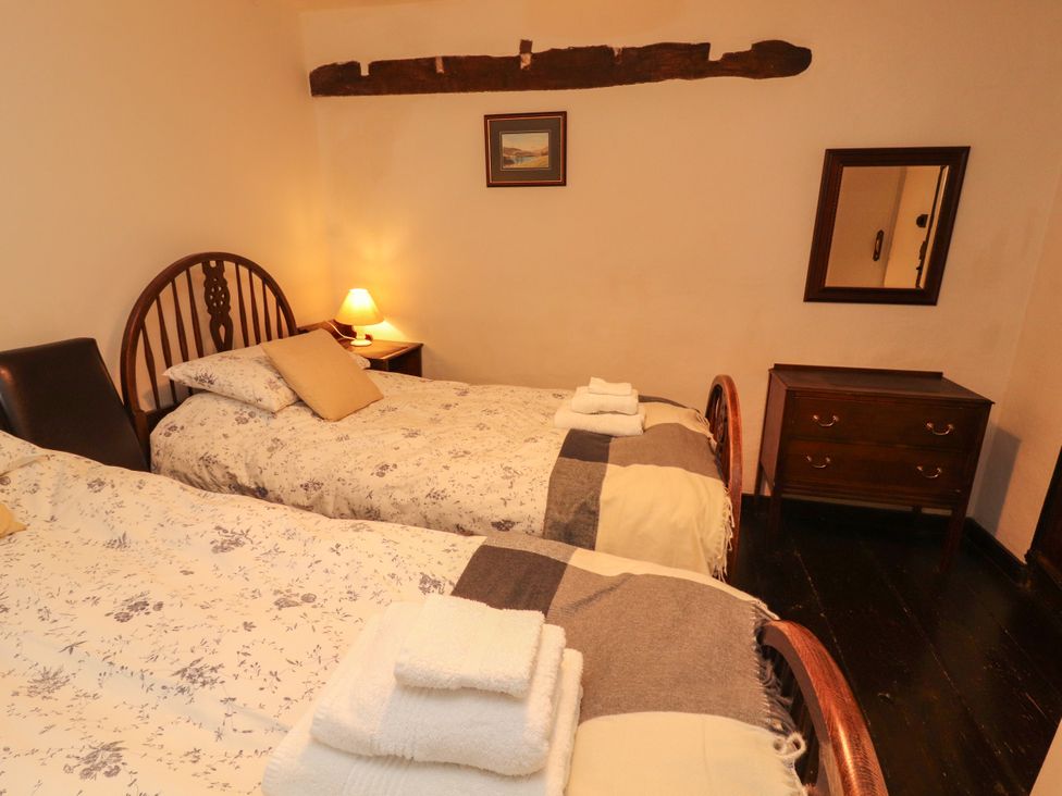 A bedroom with two beds and a nightstand at Mill Cottage in Garnett Bridge