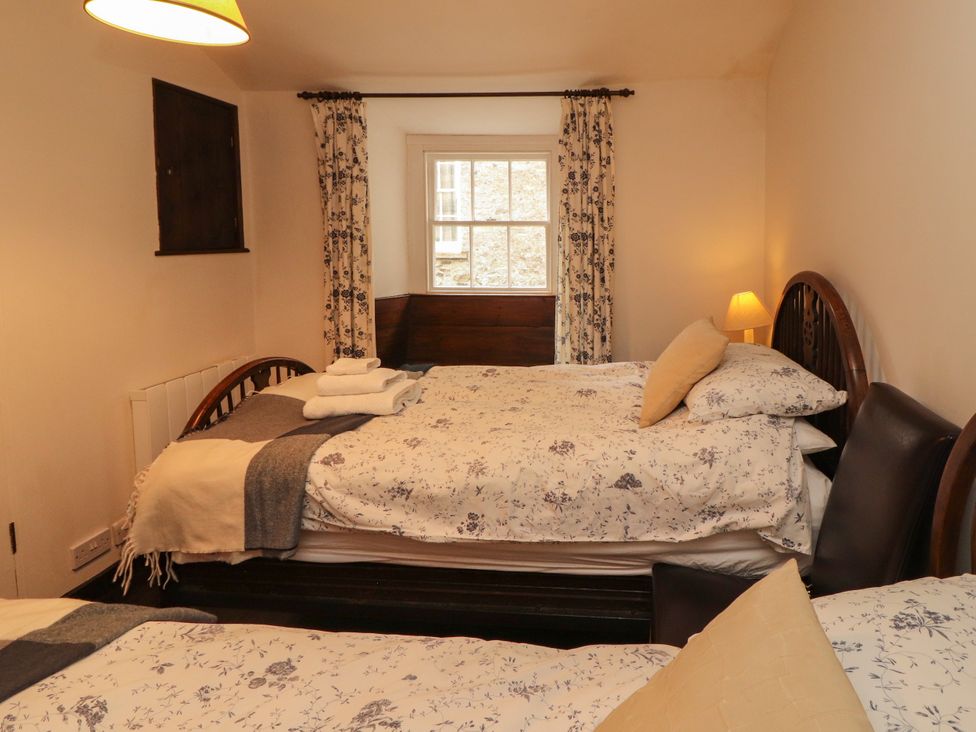 A bedroom with two beds and a lamp at Mill Cottage in Garnett Bridge
