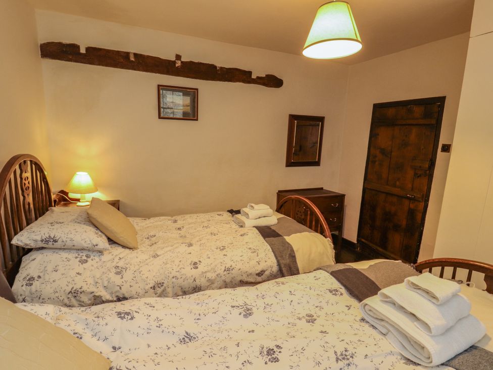 A bedroom with two beds and a lamp at Mill Cottage in Garnett Bridge