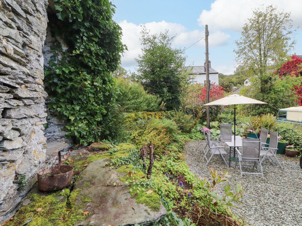 A garden with a stone wall and seating area at Mill Cottage in Garnett Bridge