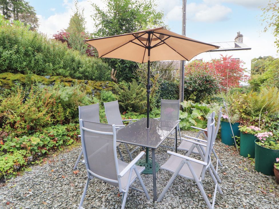 A garden with a table and chairs under an umbrella at Mill Cottage Garnett Bridge