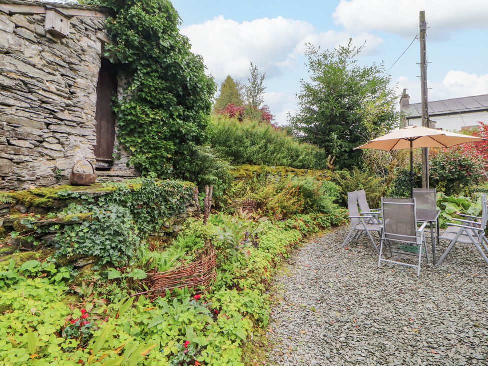 A garden with a stone wall and outdoor furniture at Mill Cottage in Garnett Bridge