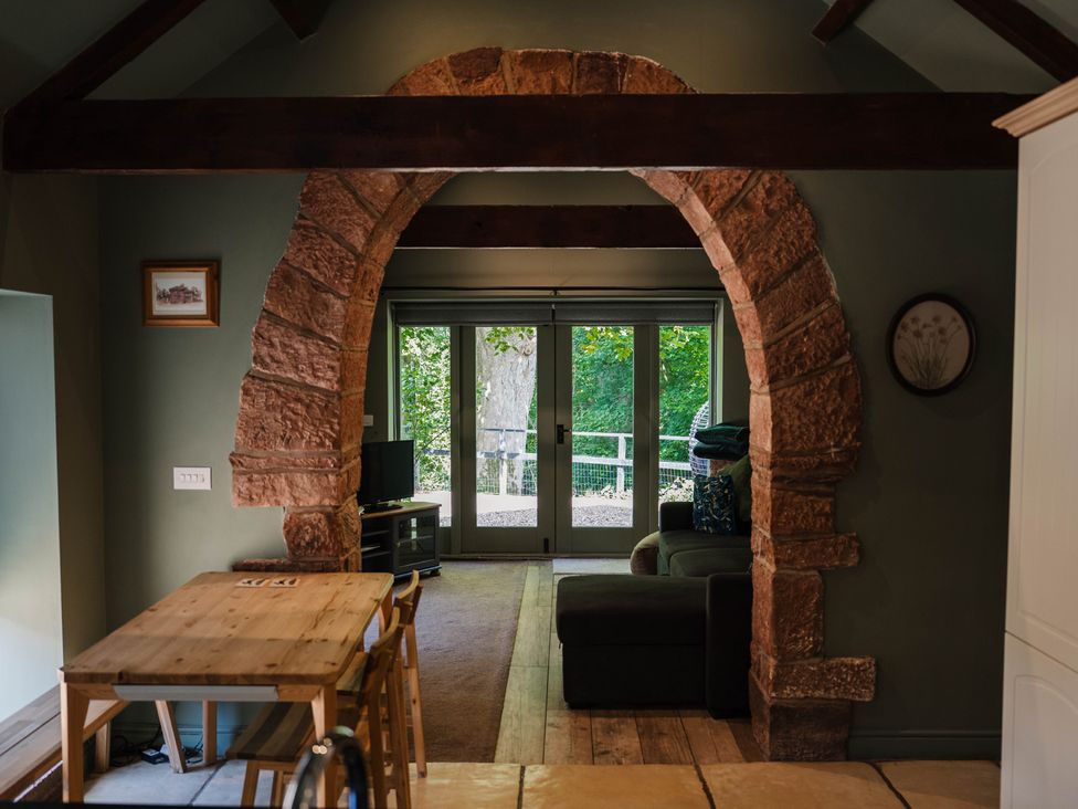 A living room with an archway leading to a patio at Carwinley Mill House Cottage Longtown