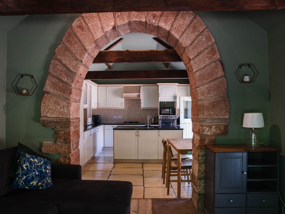 A kitchen with archway and dining table at Carwinley Mill House Cottage, Longtown