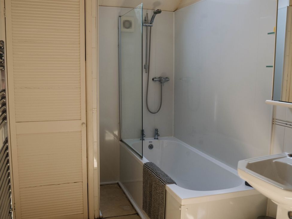 A bathroom with a bathtub and shower at Carwinley Mill House Cottage in Longtown