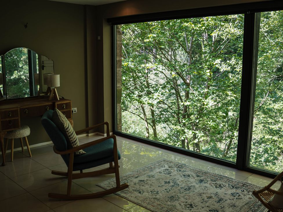 A living room with a rocking chair and window view at The Heronry in Longtown
