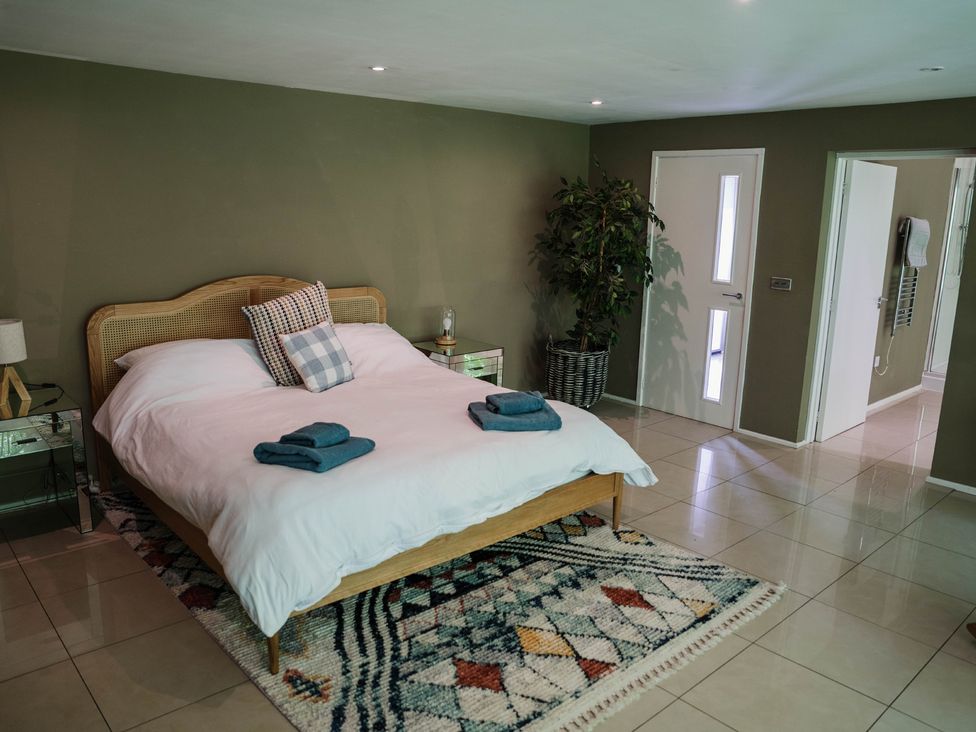 A bedroom with a bed and towels on a nightstand at The Heronry Longtown