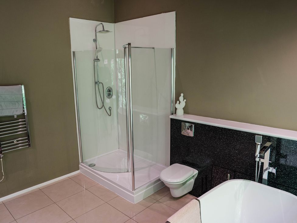 A bathroom with a shower, toilet, and bathtub at The Heronry in Longtown