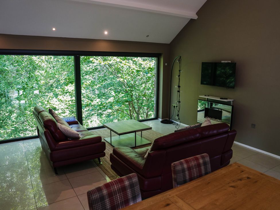 A living room with a television and large windows at The Heronry in Longtown