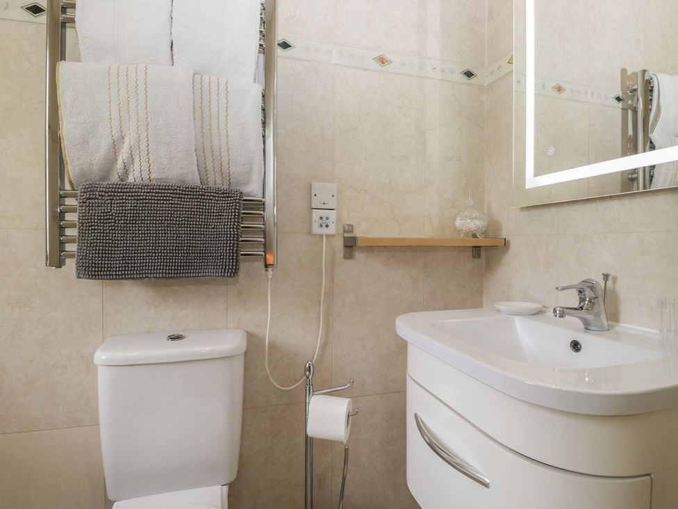 A bathroom with a toilet, sink, towels, and mirror at Stonegarth Cottage in Grasmere