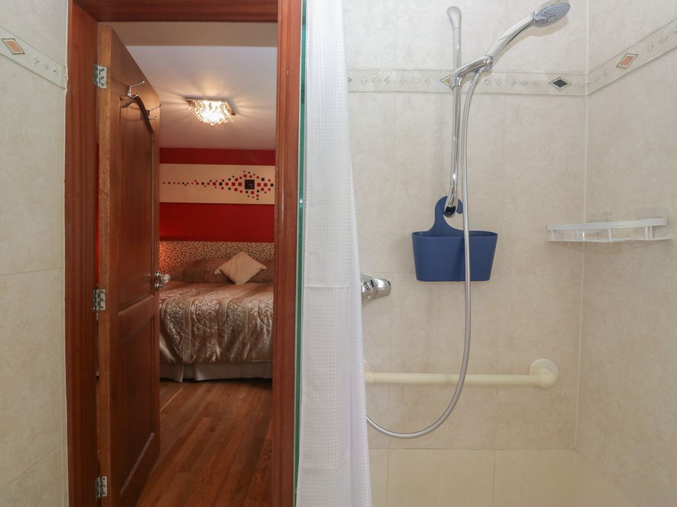A bathroom with a shower and a door leading to a bedroom at Stonegarth Cottage in Grasmere