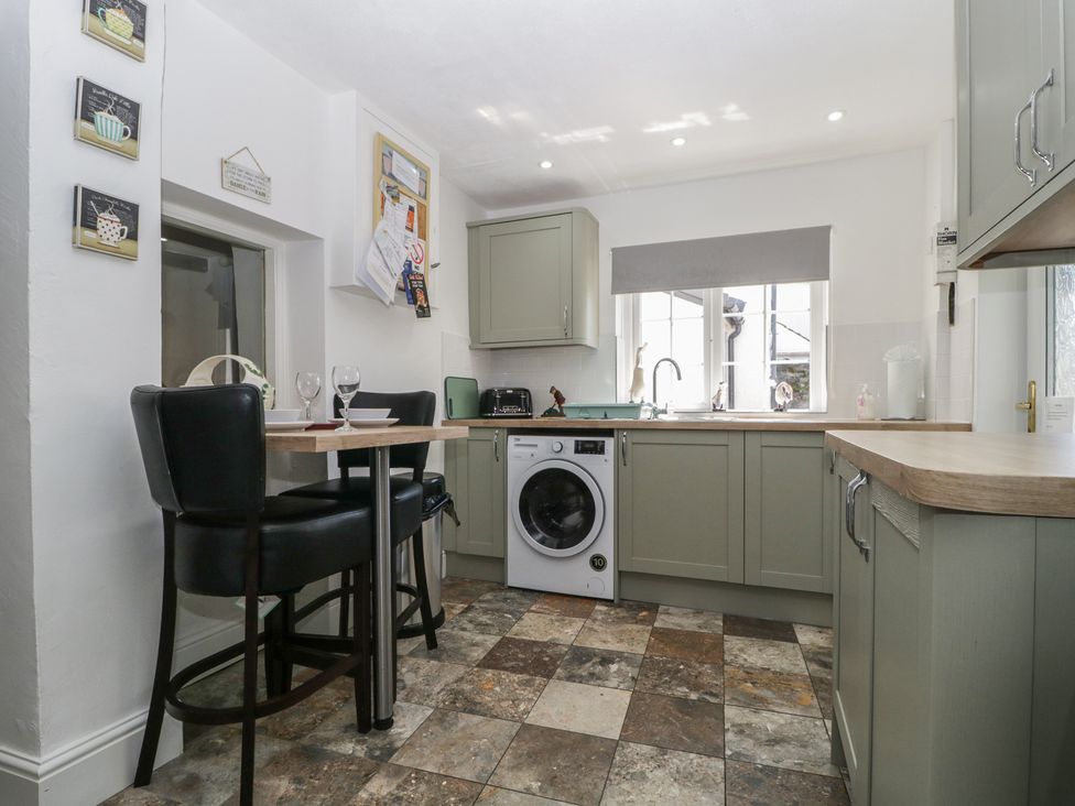 A kitchen with a table and stools at Fountain Cottage in Keswick