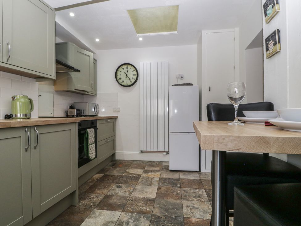A kitchen with a refrigerator and dining table at Fountain Cottage in Keswick