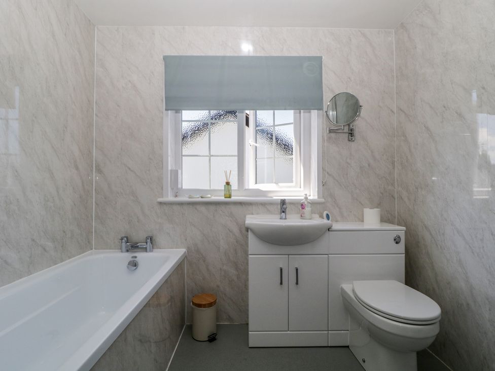 A bathroom with a bath tub, sink, and toilet at Fountain Cottage in Keswick
