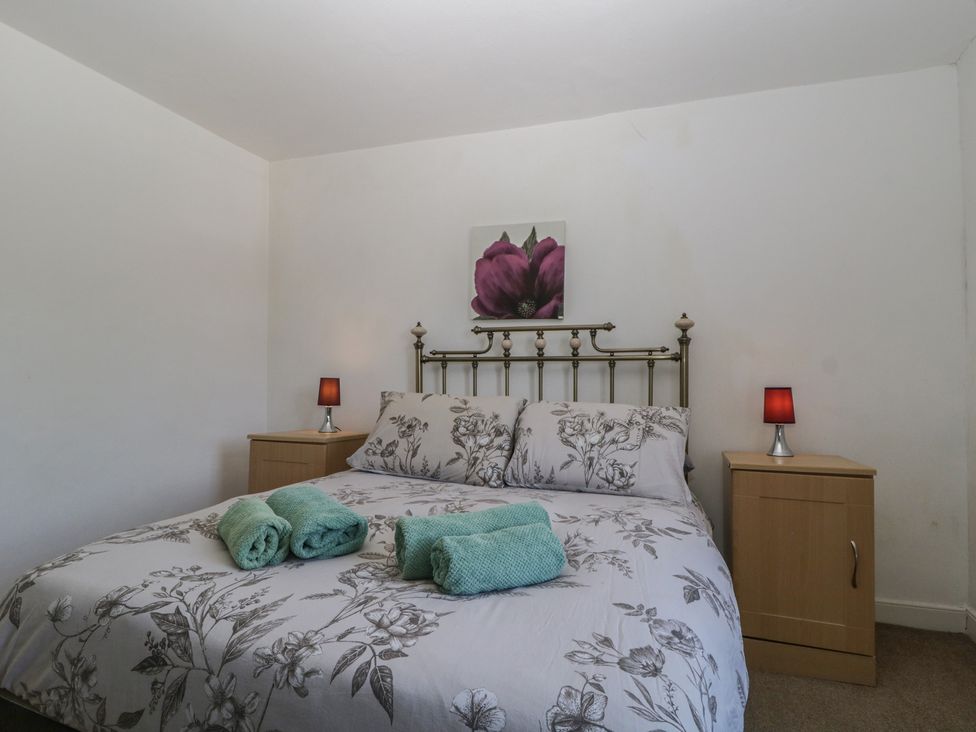 A bedroom with a bed and nightstands at Fountain Cottage in Keswick