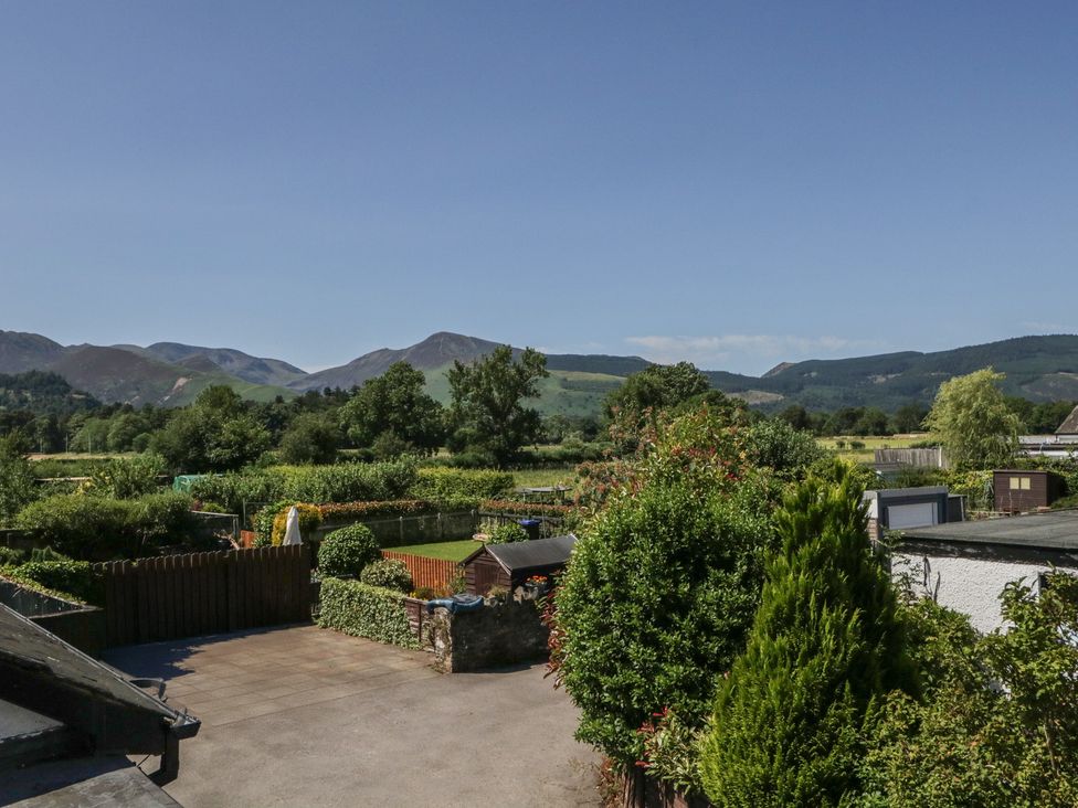 A view of a garden with trees and mountains in the background at Fountain Cottage in Keswick