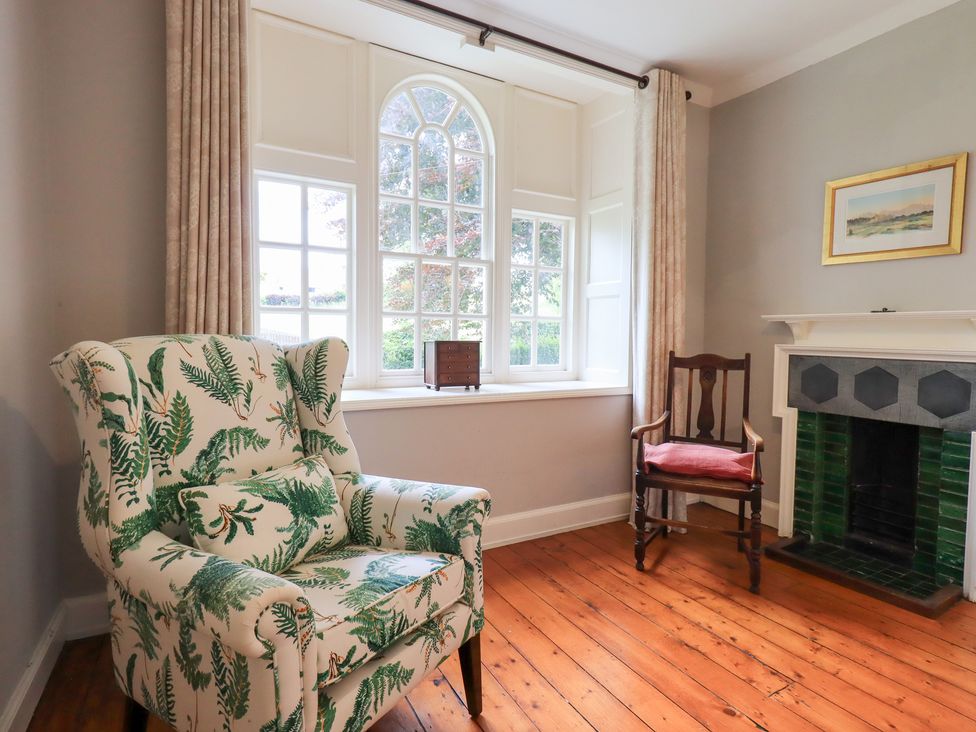A living room with a patterned chair and fireplace at Little Ellers Portinscale near Keswick