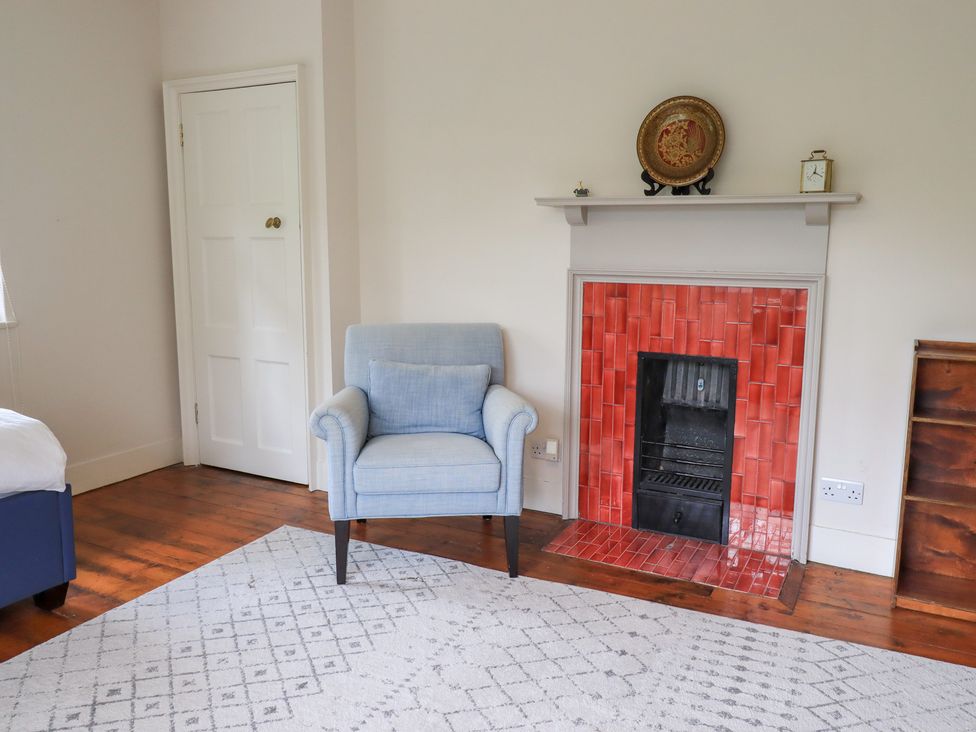 A living room with a chair and fireplace at Little Ellers in Portinscale near Keswick