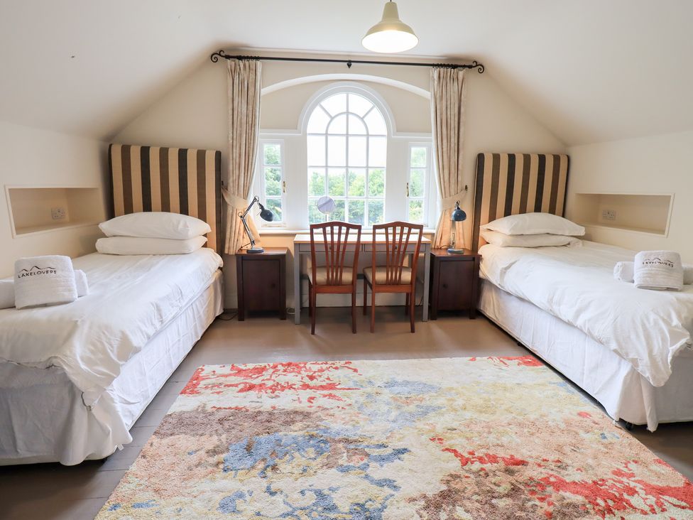 A bedroom with two beds and a table and chairs at Little Ellers in Portinscale near Keswick